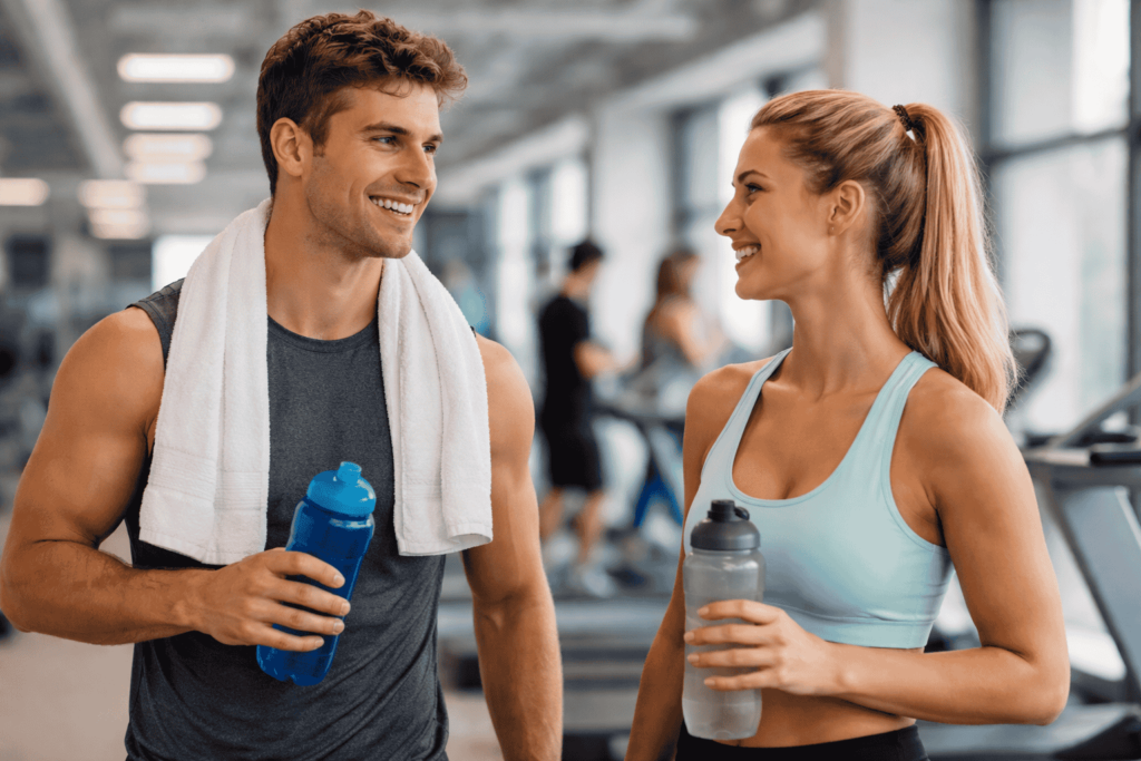 Man and woman holding water bottles in a gym representing safe exercise after wisdom teeth removal recovery