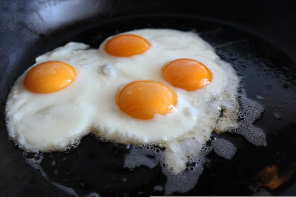 Four eggs cooking in a pan, illustrating protein content per serving