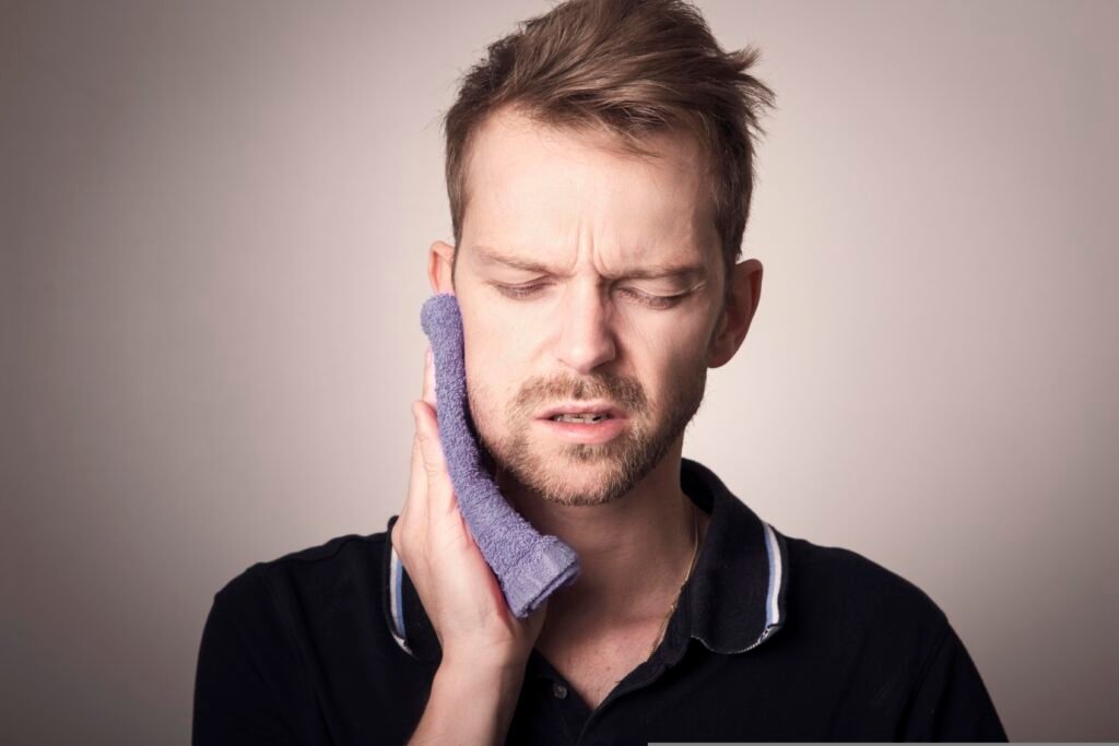 Boy holding his cheek with eyes closed due to toothache pain