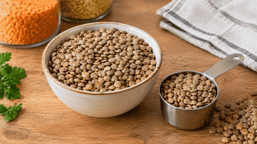 Bowl of dry lentils with a measuring cup on a wooden kitchen table